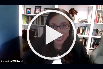 Woman with red glasses and dark brown hair in front of a white bookshelf