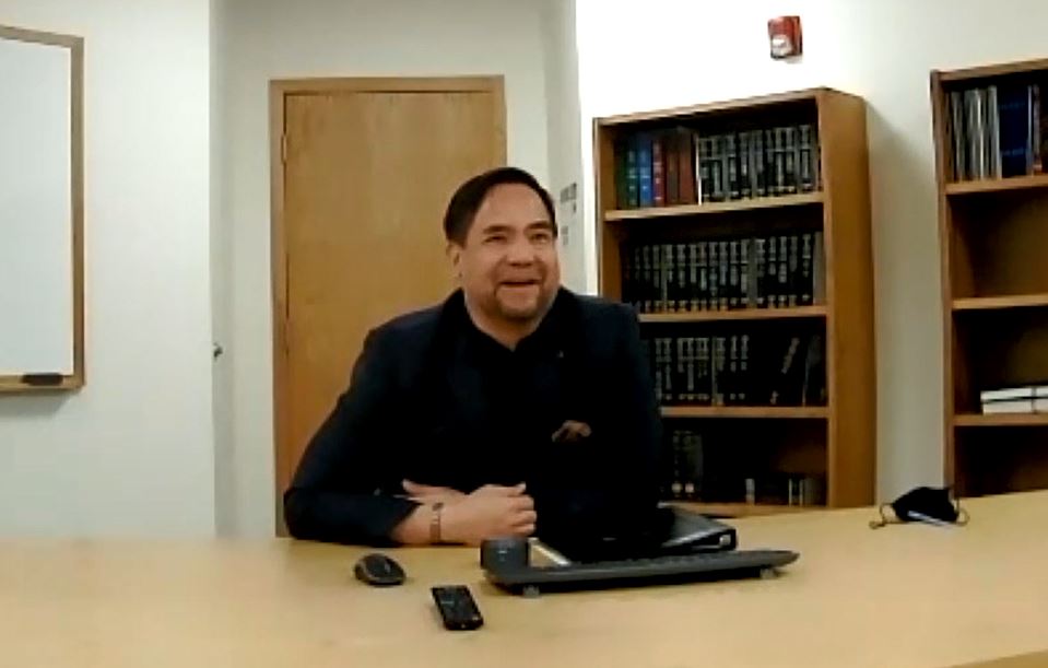 Utah State Attorney General Sean Reyes sitting in front of bookshelf in conference room