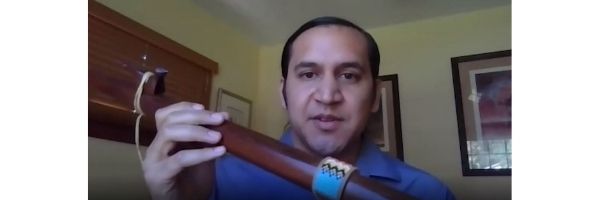 Man holding wooden flute with blue beading