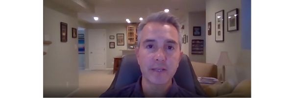 Man sitting in black chair in room with white walls