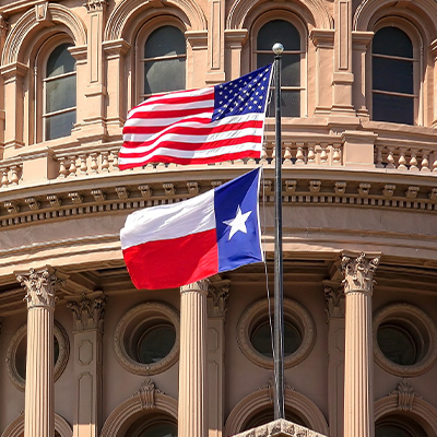 Texas state capitol building with Texas flag and U.S. flag